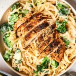 A plate of creamy zucchini noodle chicken alfredo topped with fresh herbs